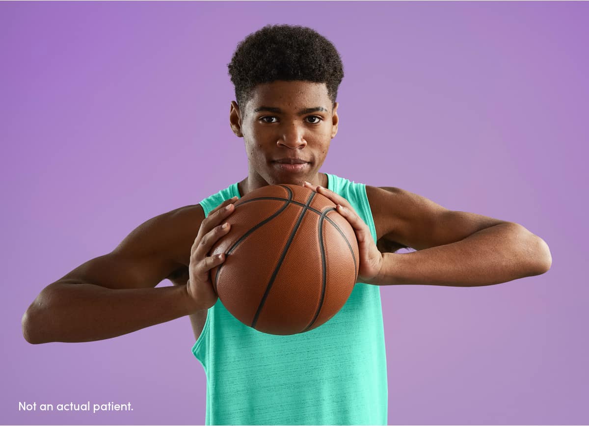 Teen boy firmly holding basketball reflects confidence with clearer skin using AKLIEF® Cream prescription acne treatment