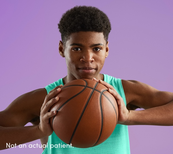Teen boy firmly holding basketball reflects confidence with clearer skin using AKLIEF® Cream prescription acne treatment