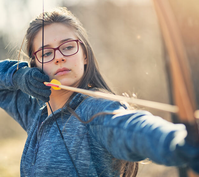 Teen girl with bow & arrow represents trifarotene, the secret weapon in AKLIEF® Cream that targets the root cause of acne